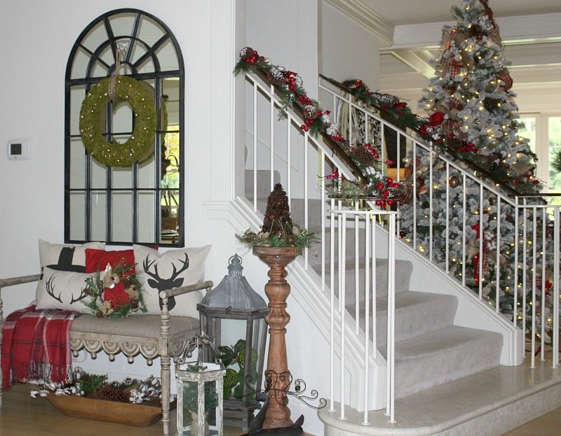 avoid holiday stress with Christmas Entryway decorated with flocked tree, mirror and bench with holiday pillows