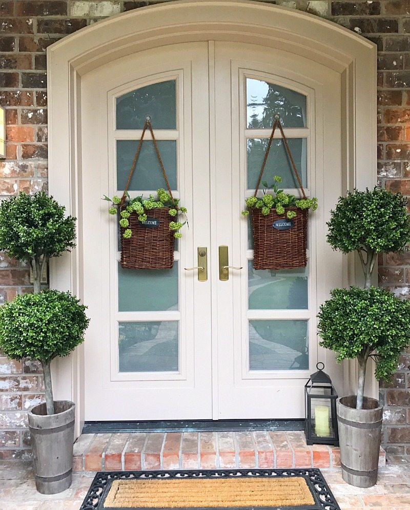 front door front porch with greenery and hanging door baskets