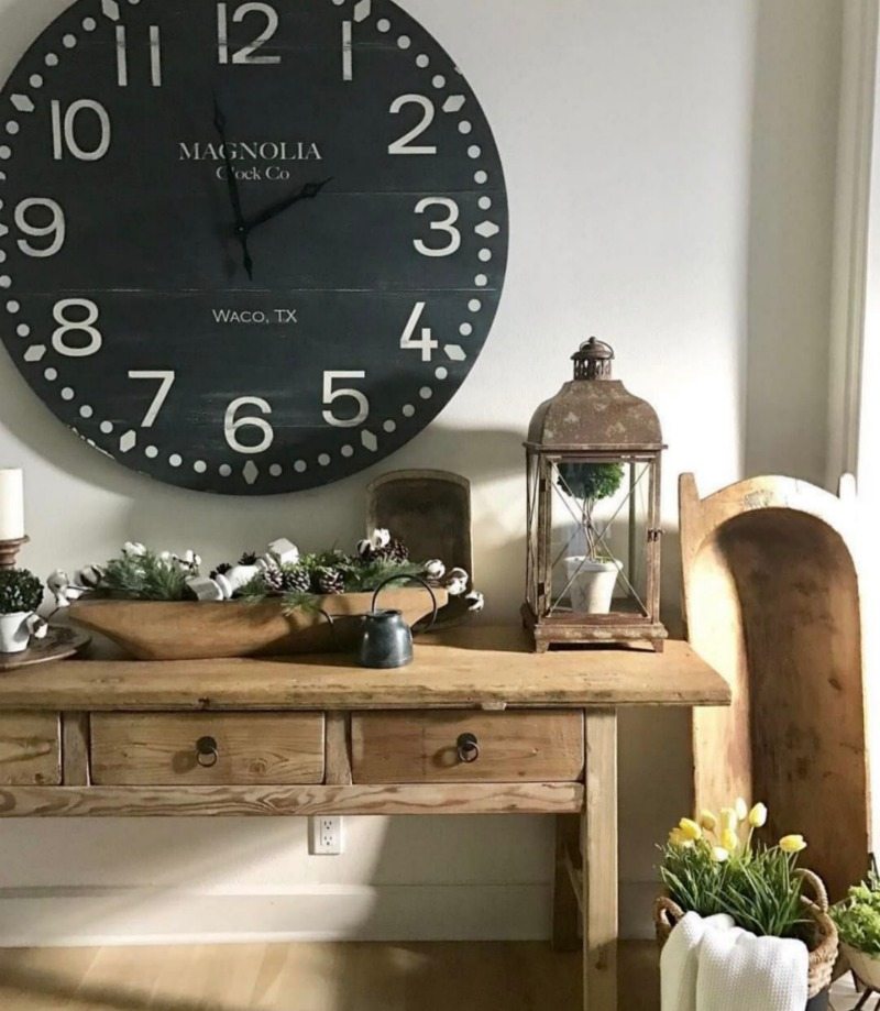 oversized clock above farmhouse table with dough bowl