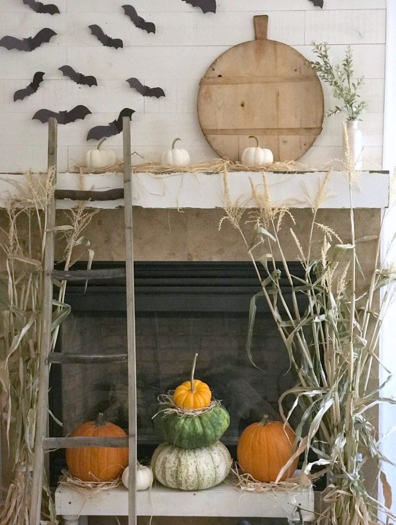 Simple acitvivity paper bats over fireplace with pumpkins and ladder