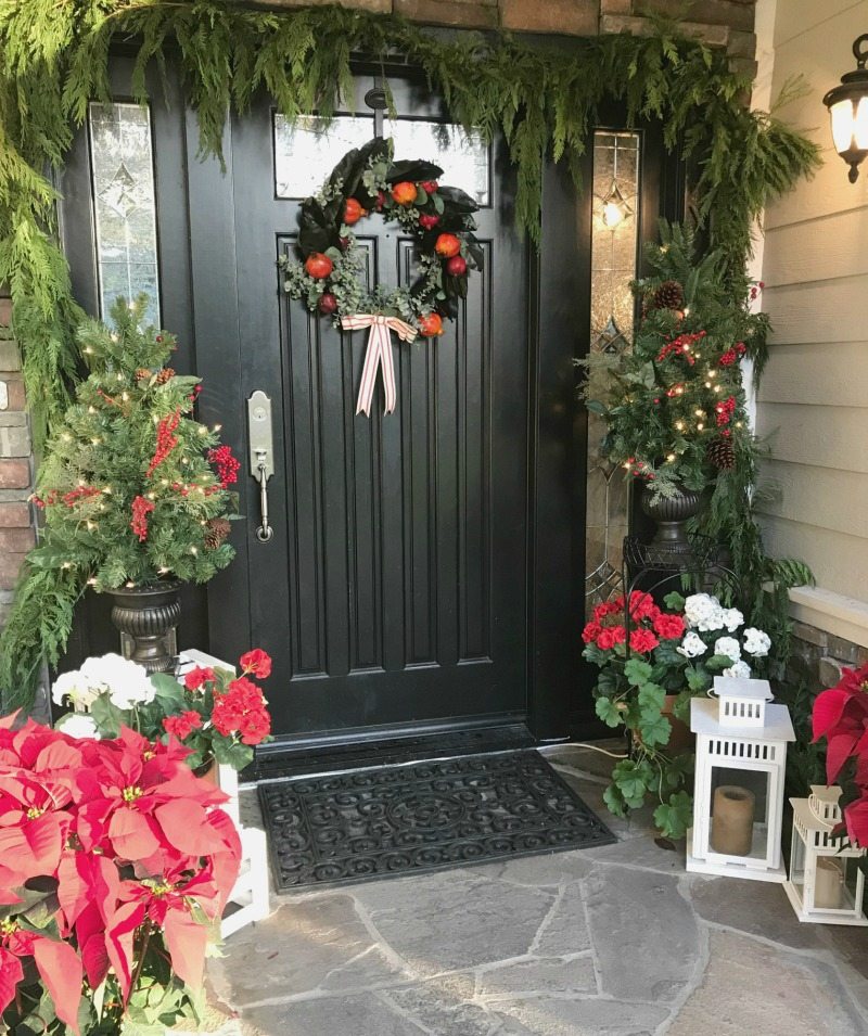 Christmas Home Tour front door decor with red poinsettas and evergreen garlands