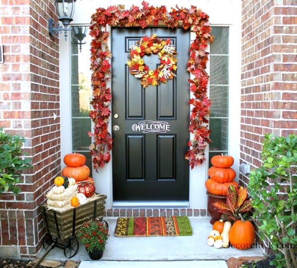 beautiful fall front door and porch with pumpkins and leaf garland