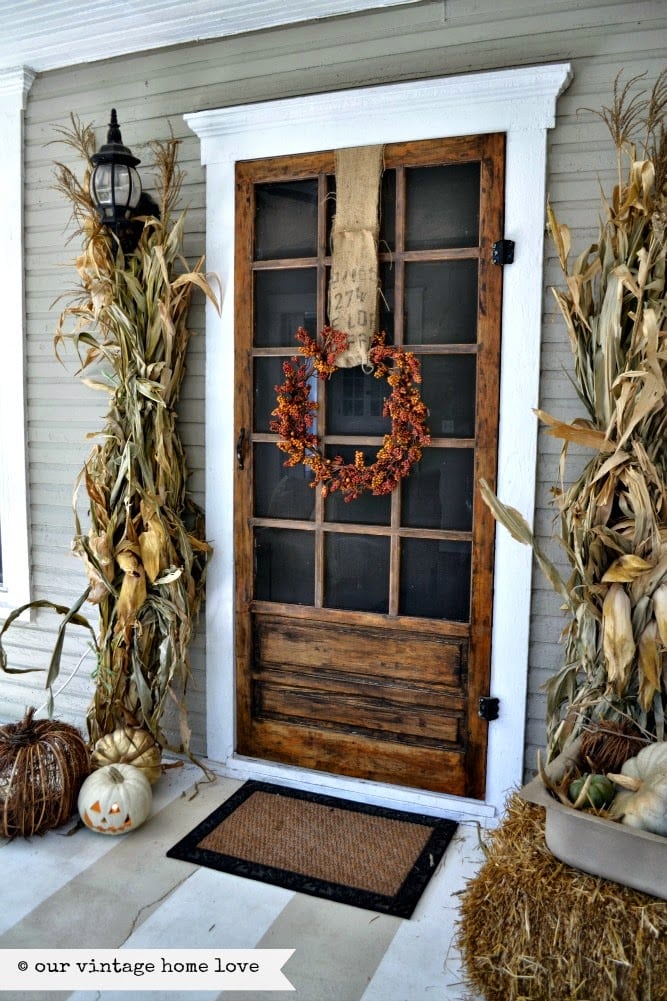 corn stalks decorate this wood door for fall