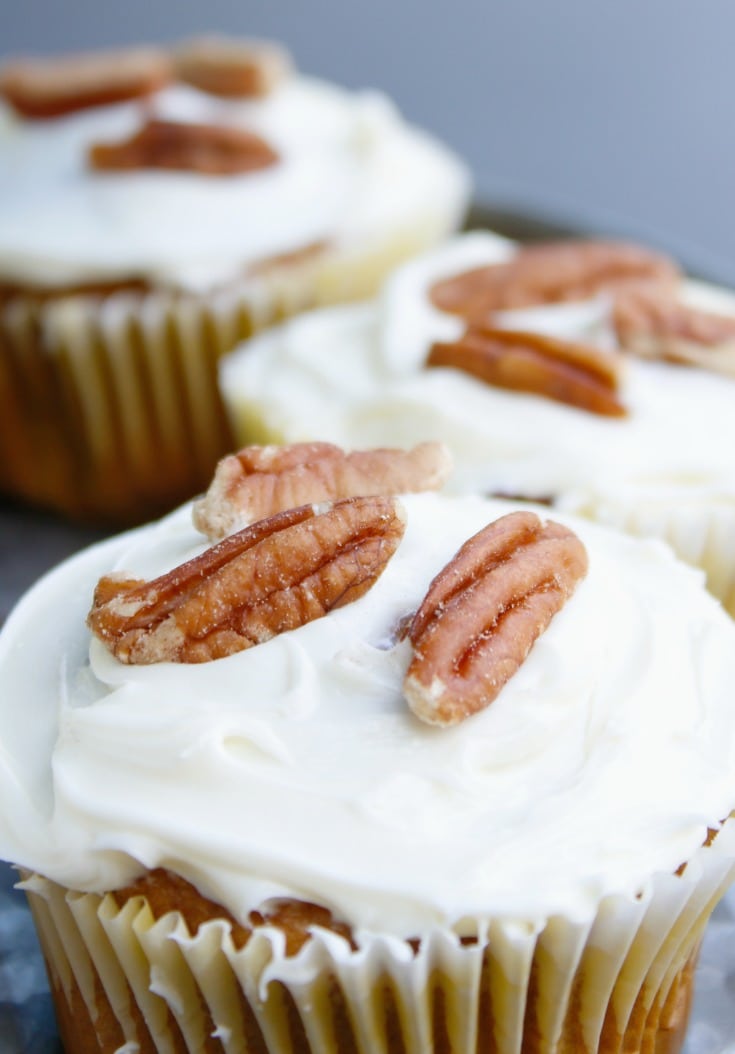 close up pumpkin spice cupcakes with cream cheese frosting and pecans