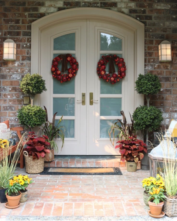 Festive fall home porch with mums and apple wreaths