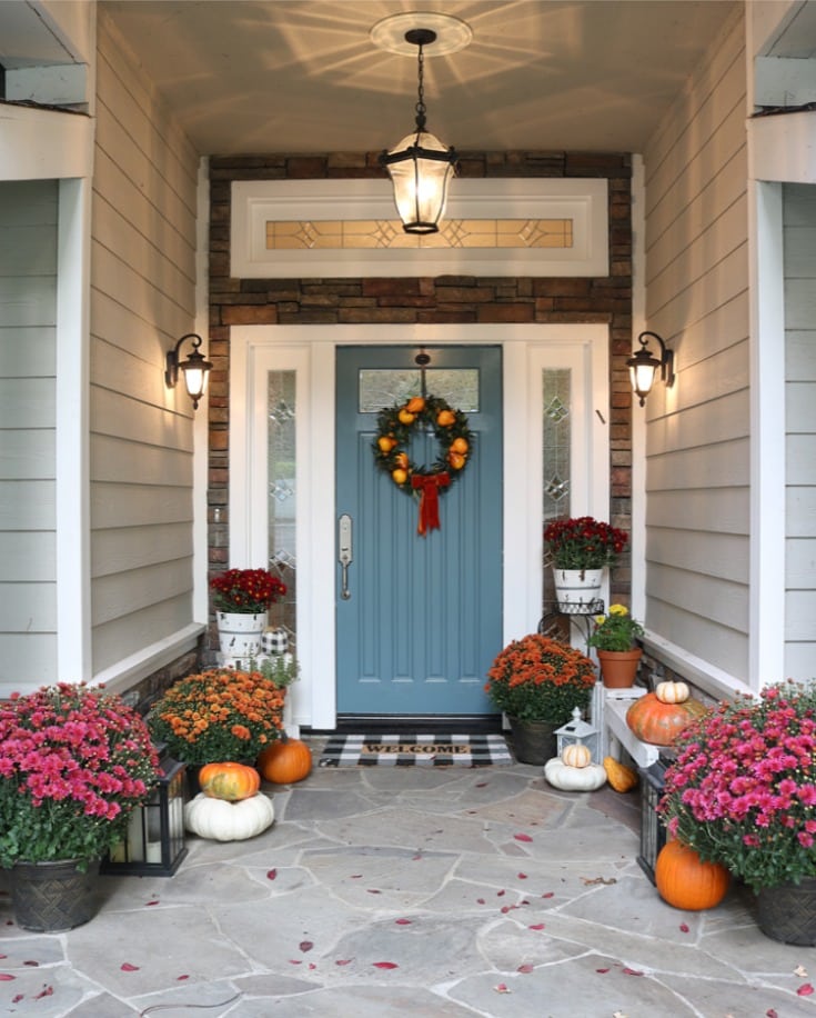 slate blue front door with bright colored mums and pumpkins for fall