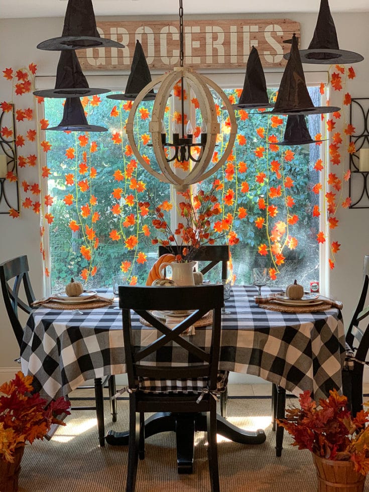 Whimsical and festive Halloween decor comes to life with floating witches hats and garlands of autumn leaves