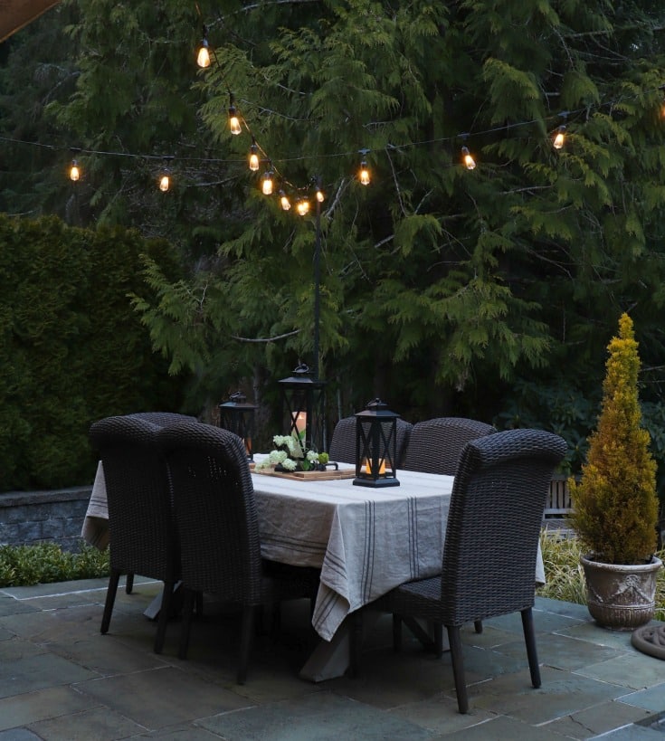 outdoor dining table with overhead string lights adds the perfect amount of mood lighting