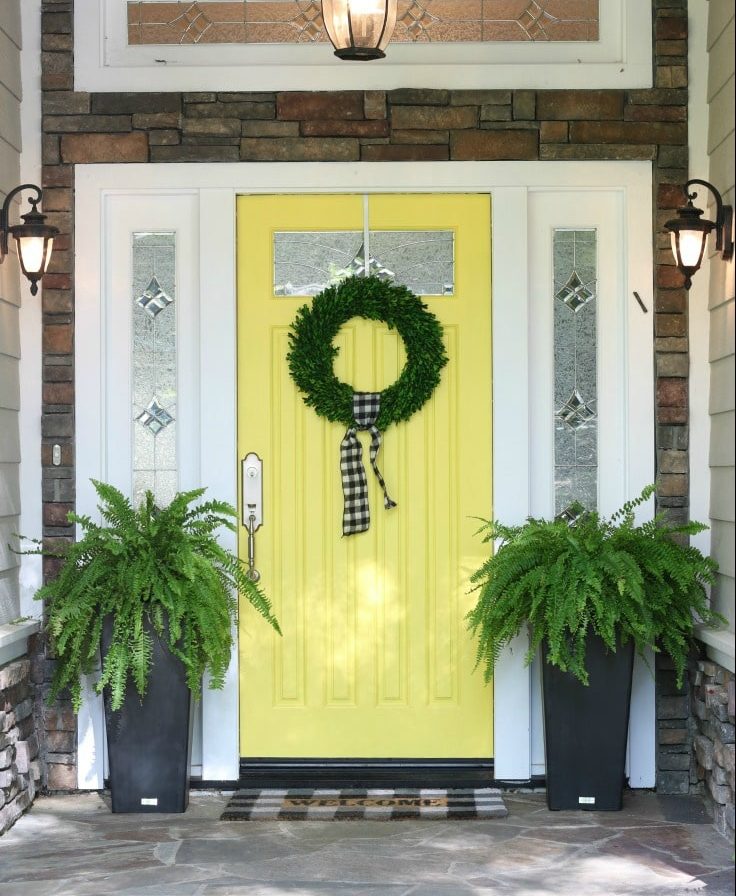 yellow painted front door with wreath