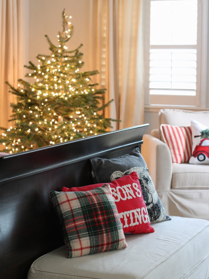 bench in Christmas bedroom with festive pillows and Christmas tree in background