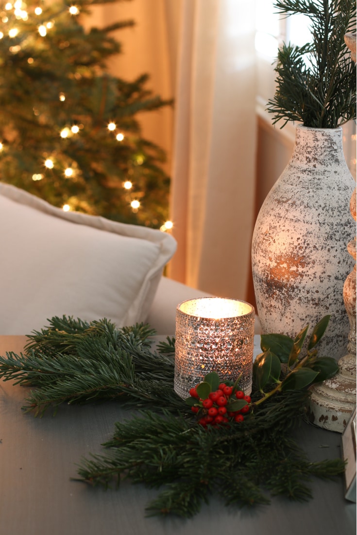holiday vignette with candle, pine tree branches and a vase