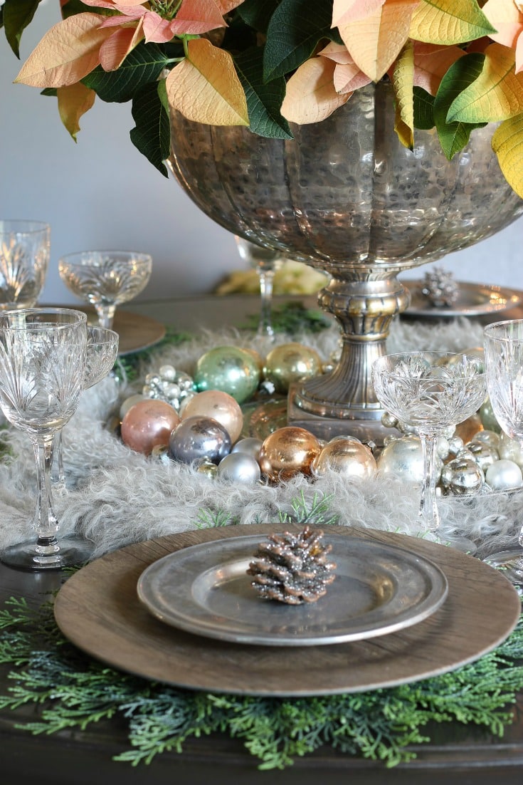 place setting detail with evergreen placemat wood charger pewter plate and glitter pinecone