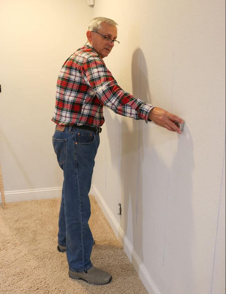 man measuring wall to find studs for shiplap wall