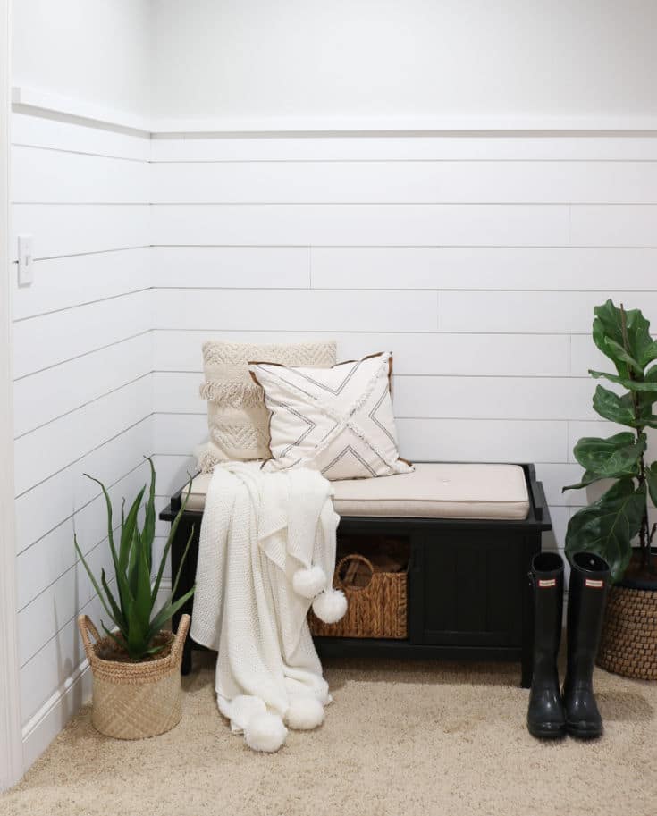front entryway with white shiplap on walls and farmhouse bench with pillows