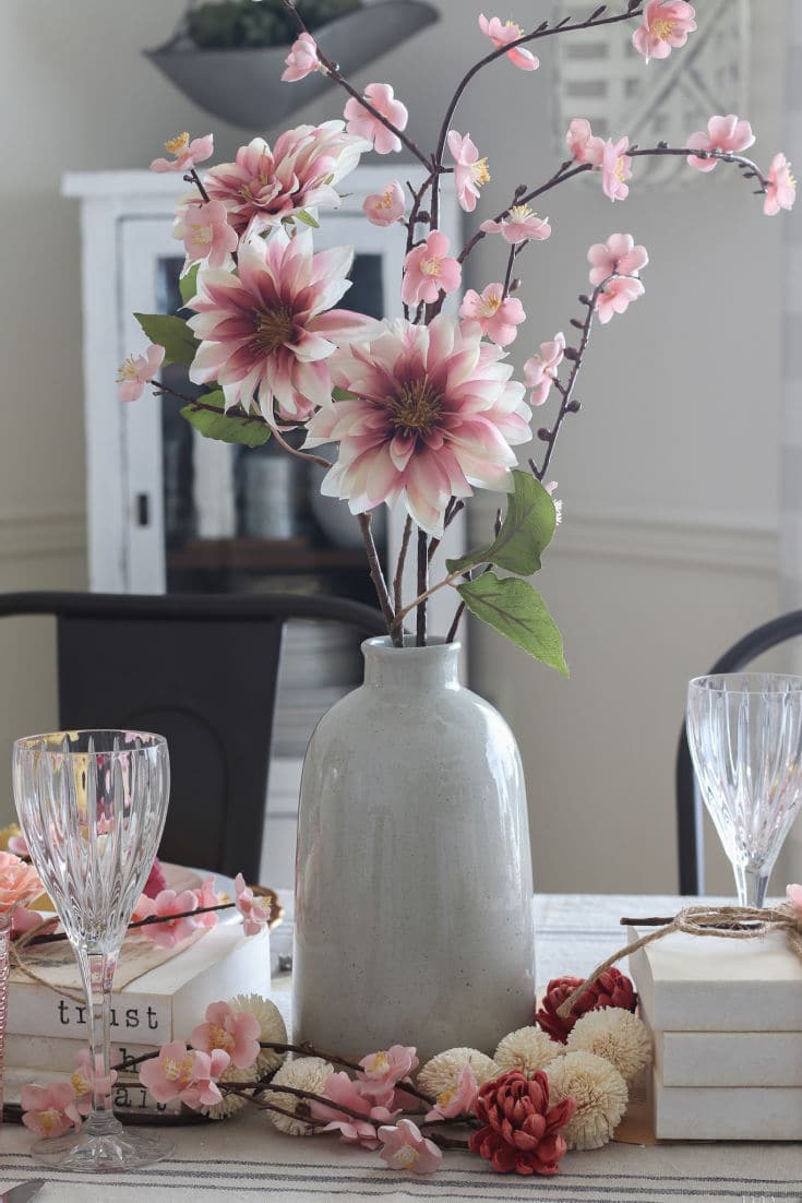 faux pink dahlia stem in ceramic vase decorates center of valentines day table