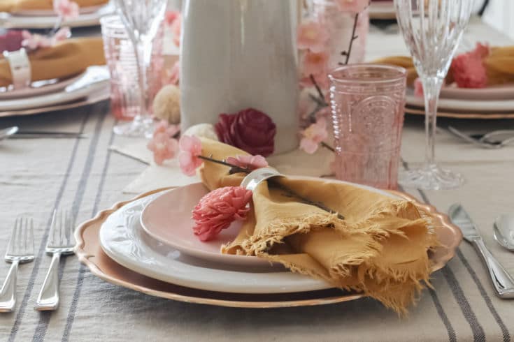 Layered pink and gold plates with gold napkin decorated with pink flowers