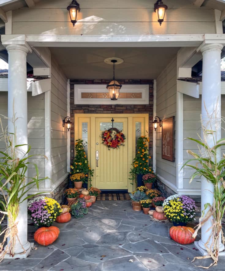 front porch with white columns and gold door with pumpkins and mums decorated for fall