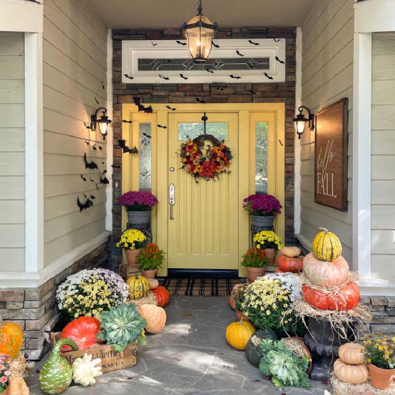 Front door decorated for Halloween with pumpkins and paper bats