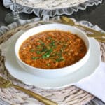 brown lentils in white bowl with Italian parsley garnish on top