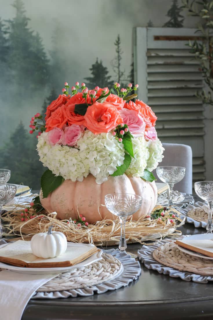 pink and coral roses and hydrangeas inside a pumpkin vase create dramatic centerpiece