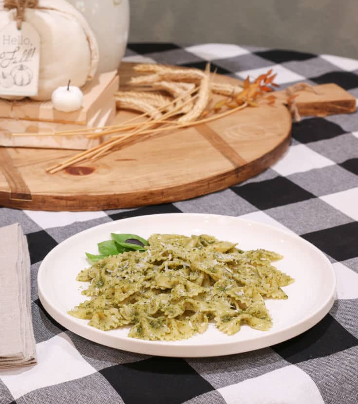 Homemade basil pesto sauce with bowtie pasta noodles on black and white buffalo plaid table cloth