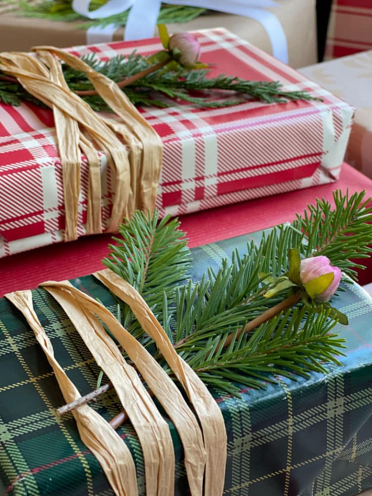 plaid Christmas wrapping paper tied with raffia and evergreen sprigs added