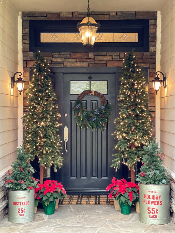 Front porch decor is easy with large alpine trees and pops of red poinsettias