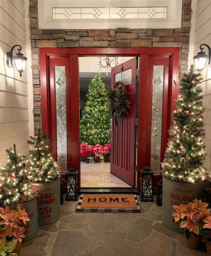 Burgundy door decorated for Christmas with festive Christmas trees and poinsettias