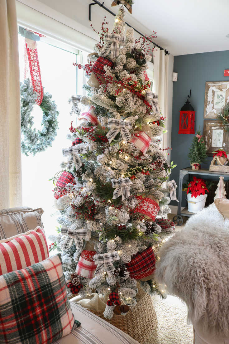 red and white Christmas tree is decorated with red ribbons and berry garland