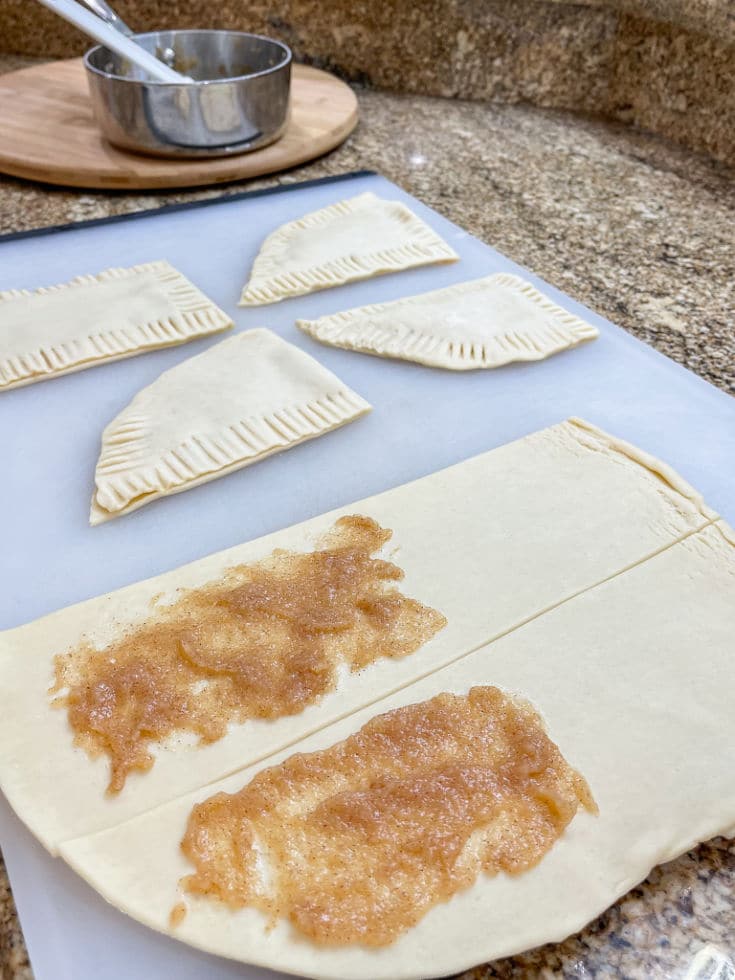 spreading apple cinnamon filling over refrigerator pie crusts to make pop tarts