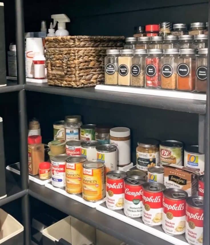 tiered shelves and labeled jars look organized and sleek in new black pantry.
