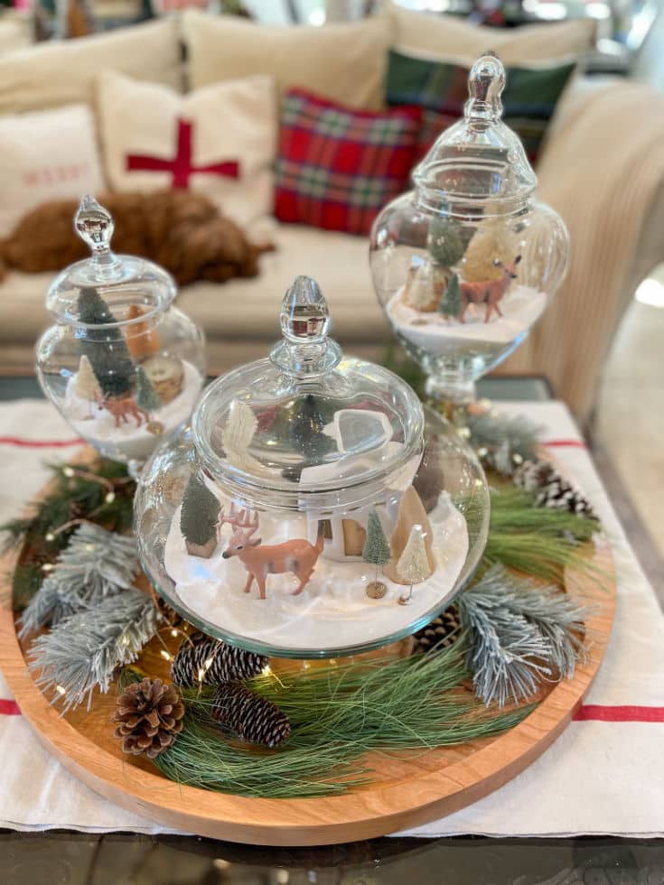 a big charcuterie board style for Christmas with a beautiful vignette of glass containers filled with a whimsical winter scene.