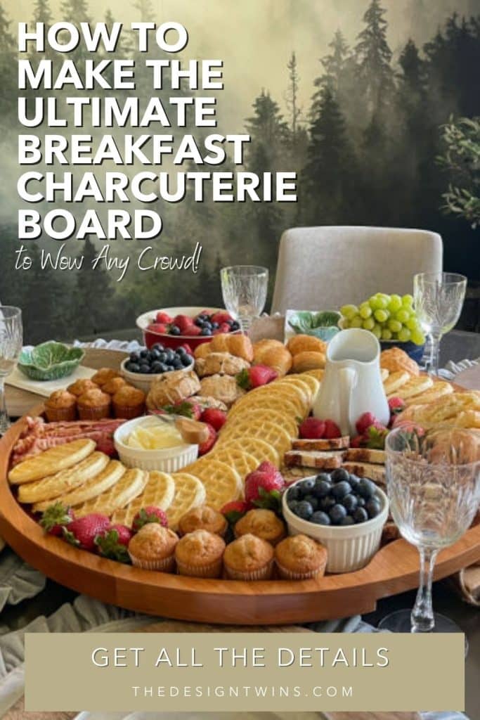 Big board featuring a charcuterie breakfast including waffles, strawberries, muffins, fruit, and bacon.