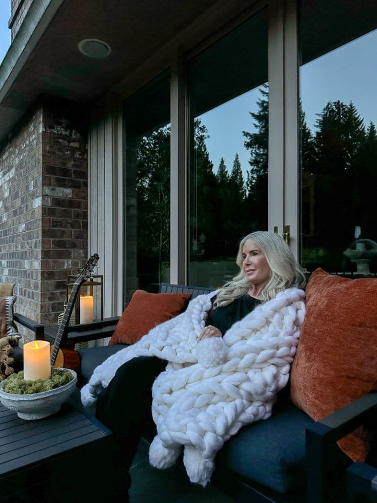 Julie on her deck enjoying her DIY outdoor decor including candles and a hand knit blanket
