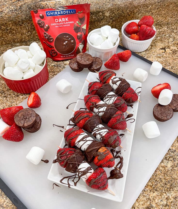 dessert kabobs with strawberries, marshmallows, mini brownie bites and finished with chocolate drizzle.