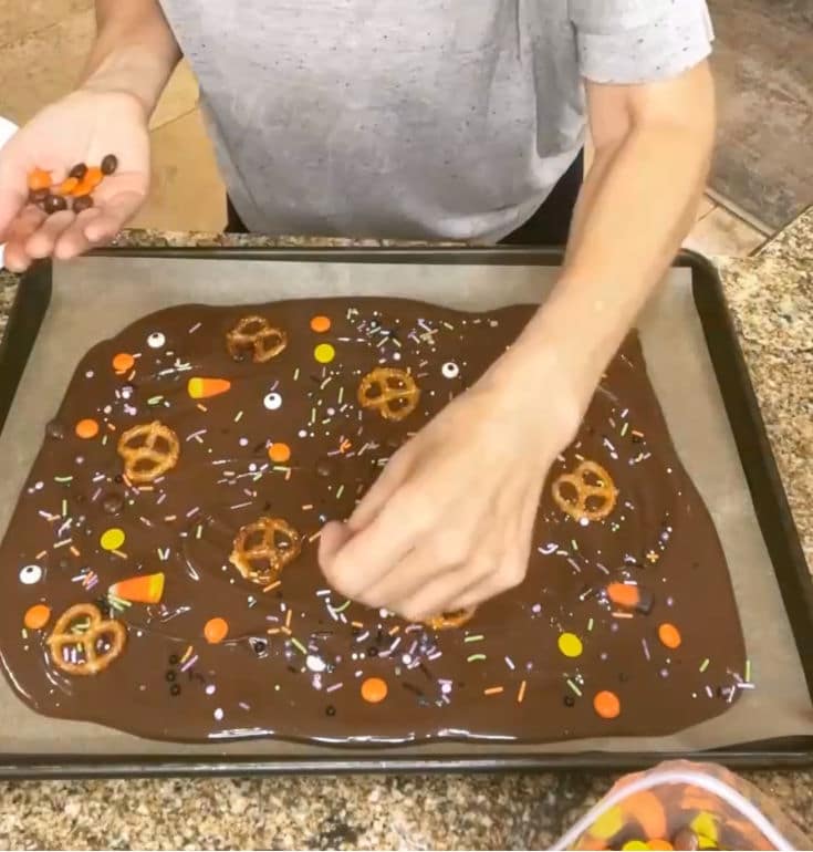 topping chocolate bark with leftover Halloween candy and pretzels