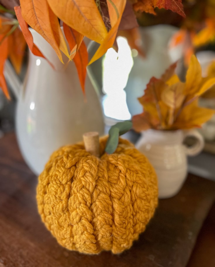 gold coloured braided yarn pumpkin completes a fall vignette on an end table.