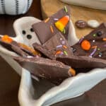 halloween chocolate bark topped with leftover halloween candy, sprinkles and pretzels