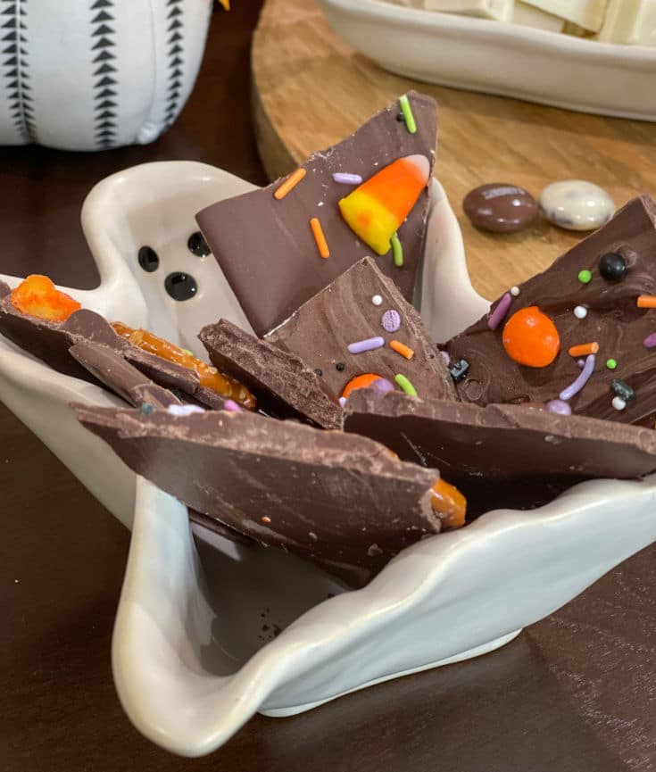 halloween chocolate bark topped with leftover halloween candy, sprinkles and pretzels
