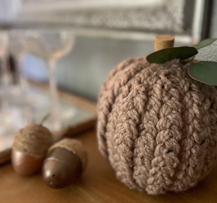 A close-up image of a faux pumpkin covered in earthy brown braided yarn, showcasing the rich, textured surface